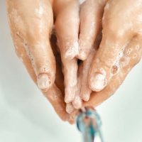Kid and adult are washing their hands. Protection against infections and viruses. Close up.